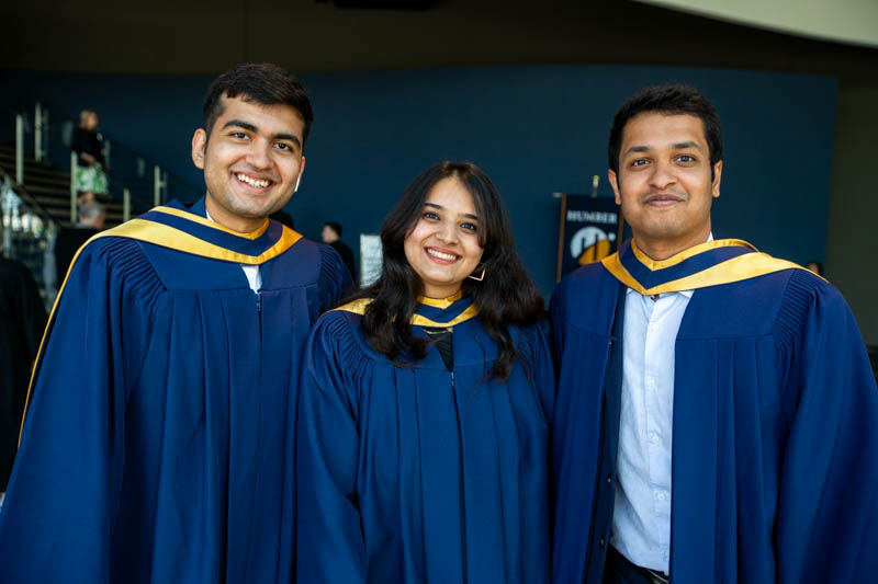 Three graduates smile for camera