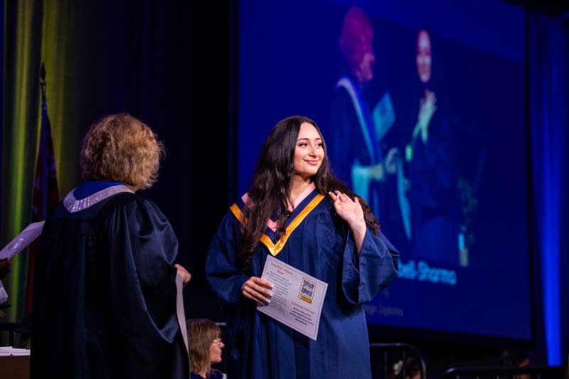Graduate waves at audience on stage