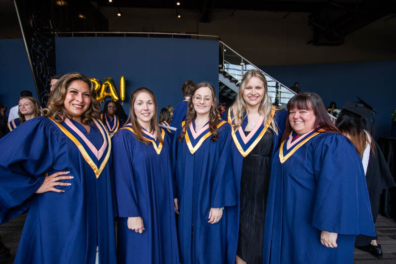 Five graduates smile for photo