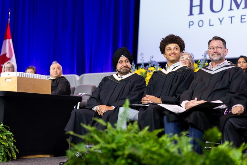 Students smiling sitting on stage