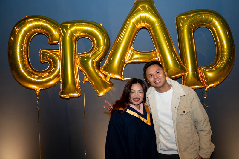 Student posing for picture in front of Grad Balloons