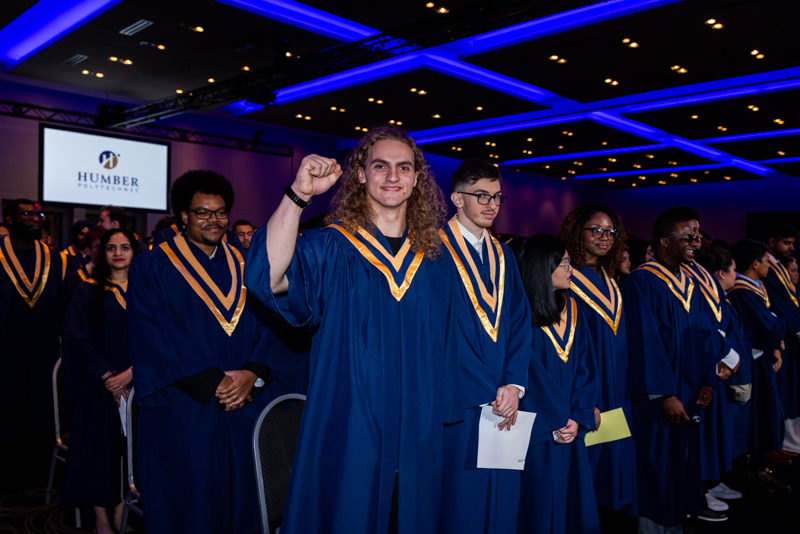 Student smiling and holding arm up