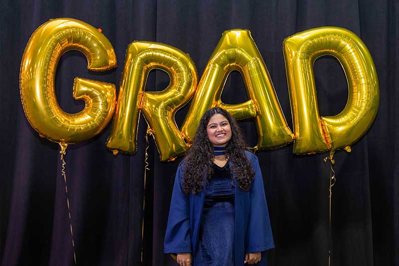 Student in front of Grad Balloons