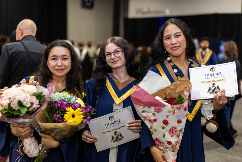 Students holding flowers and Diplomas