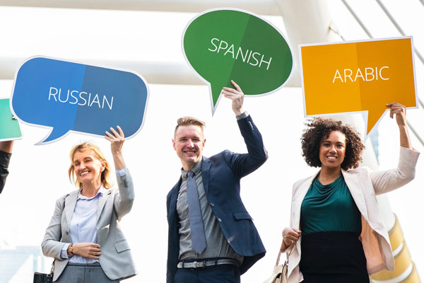 Three people holding up signs with different language names