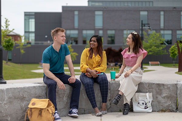 male and two females sitting outside laughing