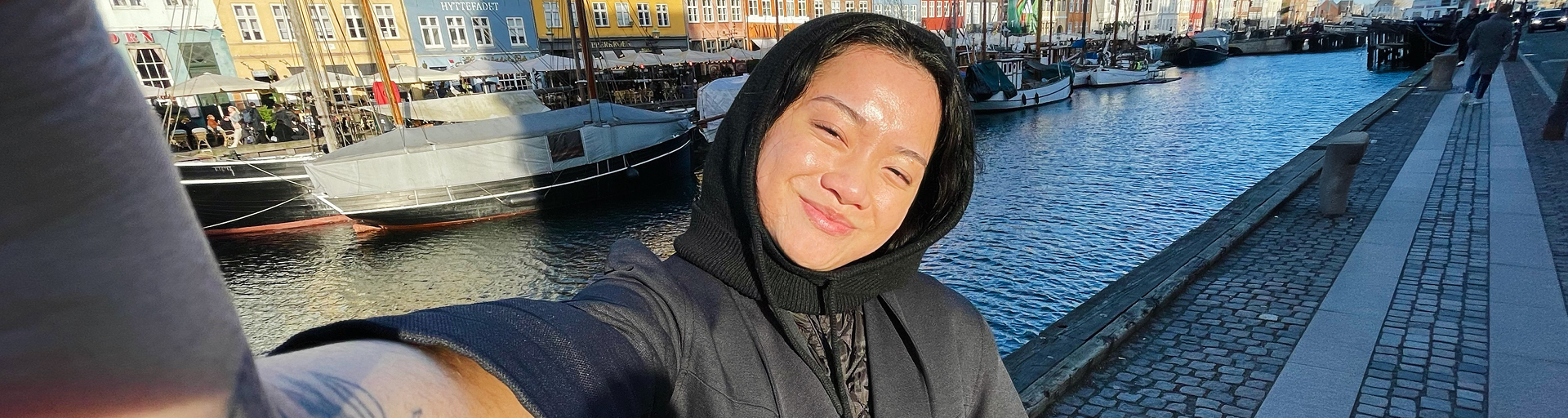 Person taking a selfie in front of boats along a dock