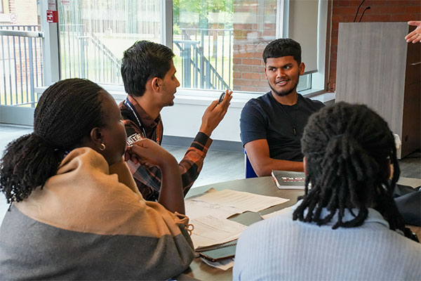 4 students sitting at a table smiling