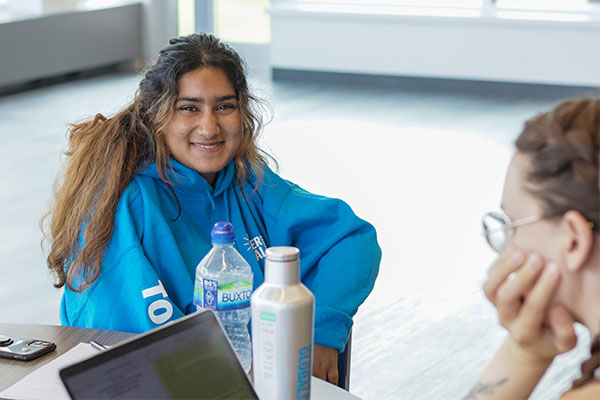 student sitting at a table smiling