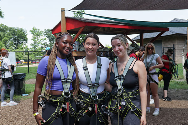three students wearing harnesses for treetop trekking 