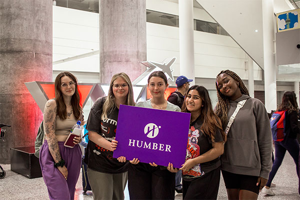 5 students at airport all holding Humber sign