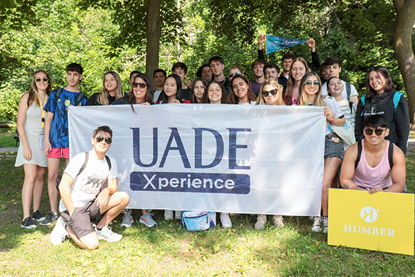 students holding a UADE Experience sign