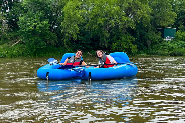 two students sitting in tubes on a river