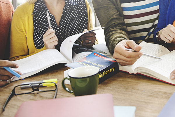 people flipping through books at a desk