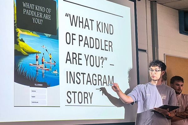 person standing in front of a large screen doing a presentation