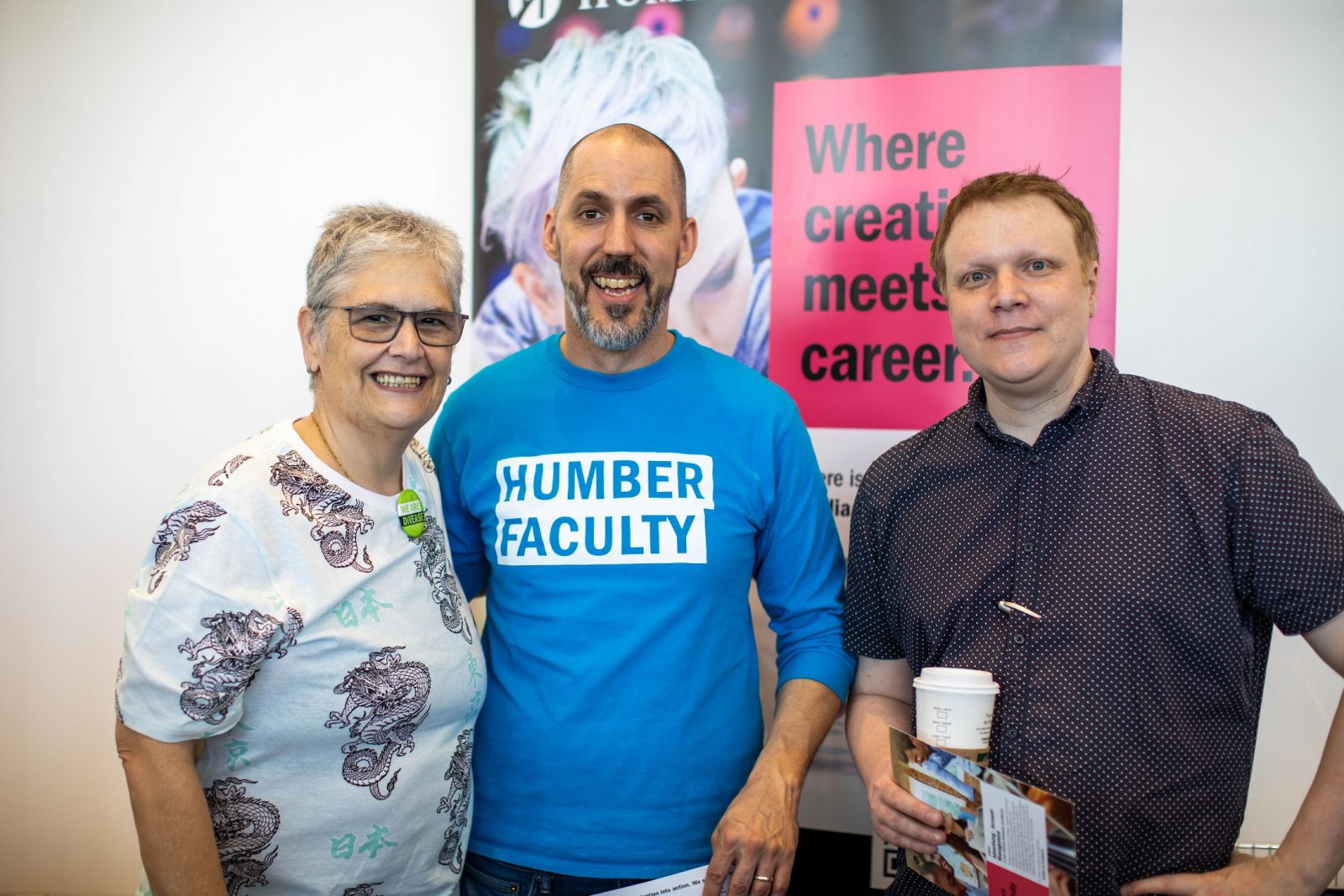 Three people posing together; one has a t-shirt that says Humber Faculty.