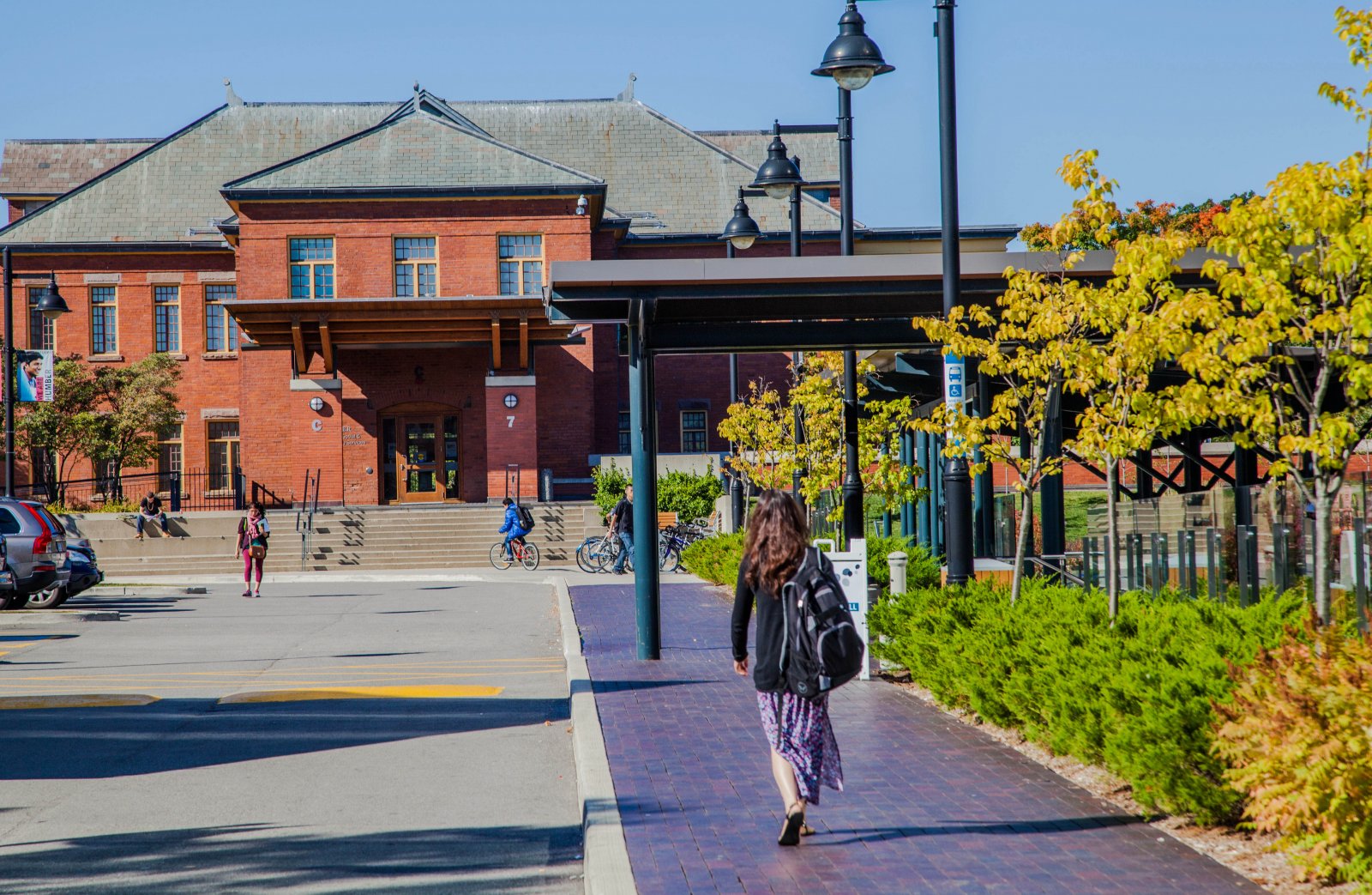 Person walking towards a red brick building on Humber's Lakeshore Campus.