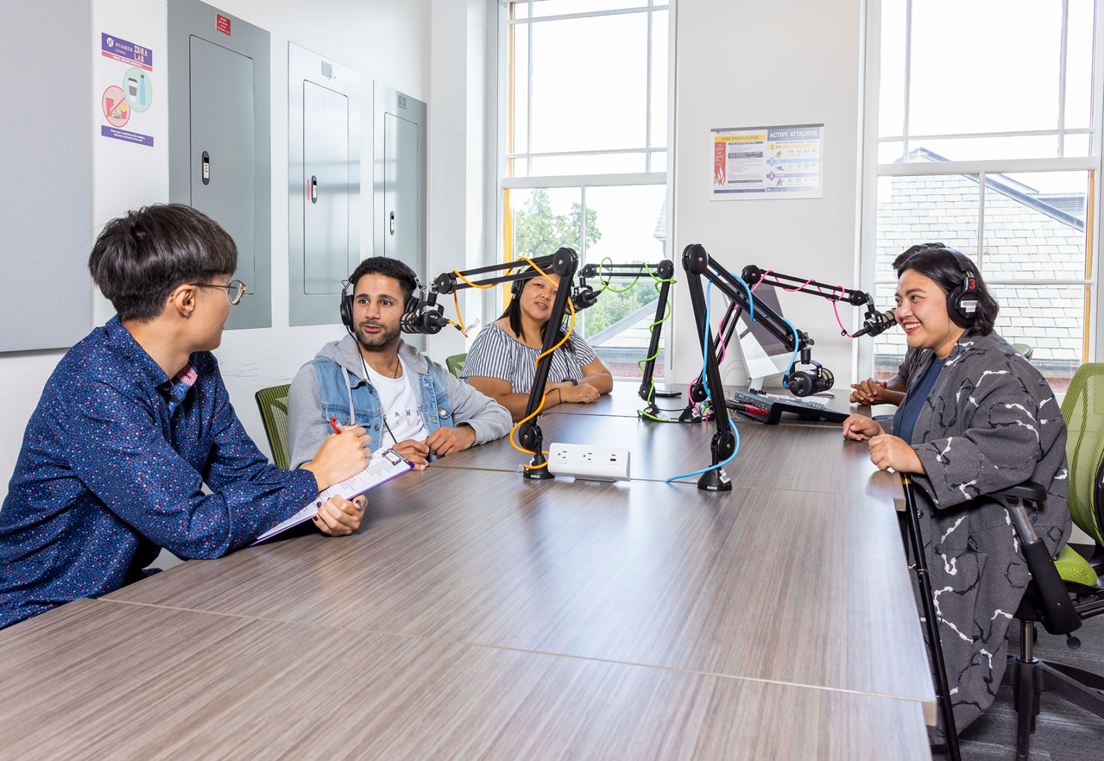 Five people sitting at a table, each with a microphone 