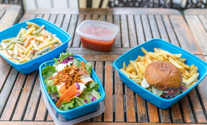 3 blue reusable containers with pasta, salad and a burger + fries