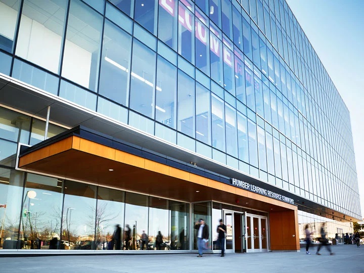 Exterior view of the Humber Learning Resource Commons building with a modern glass facade, showing people walking near the entrance.