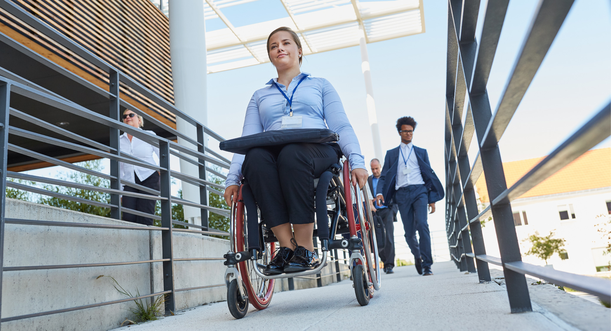 A woman in a wheelchair and several people using a wheelchair ramp