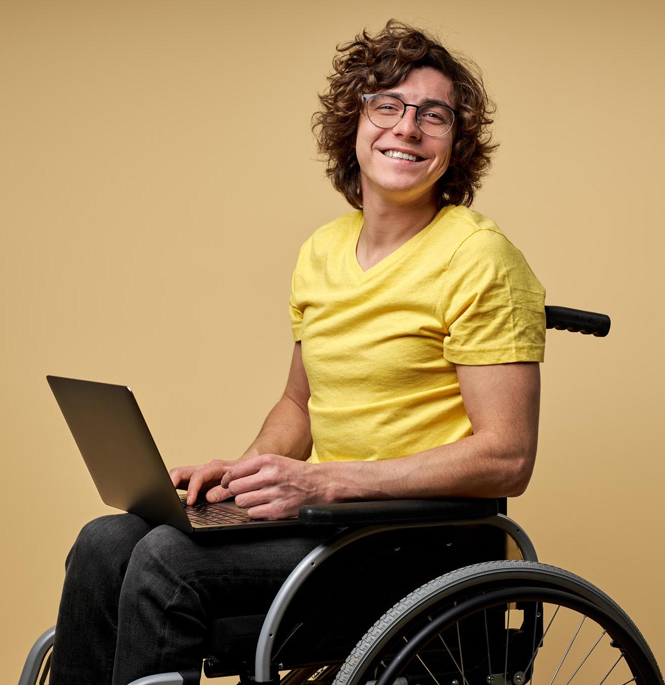 Disabled man sits in a wheelchair with laptop, working online