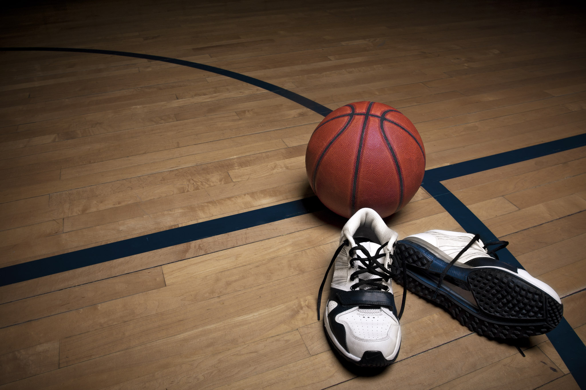 A basketball next  to basketball shoes on a basketball court