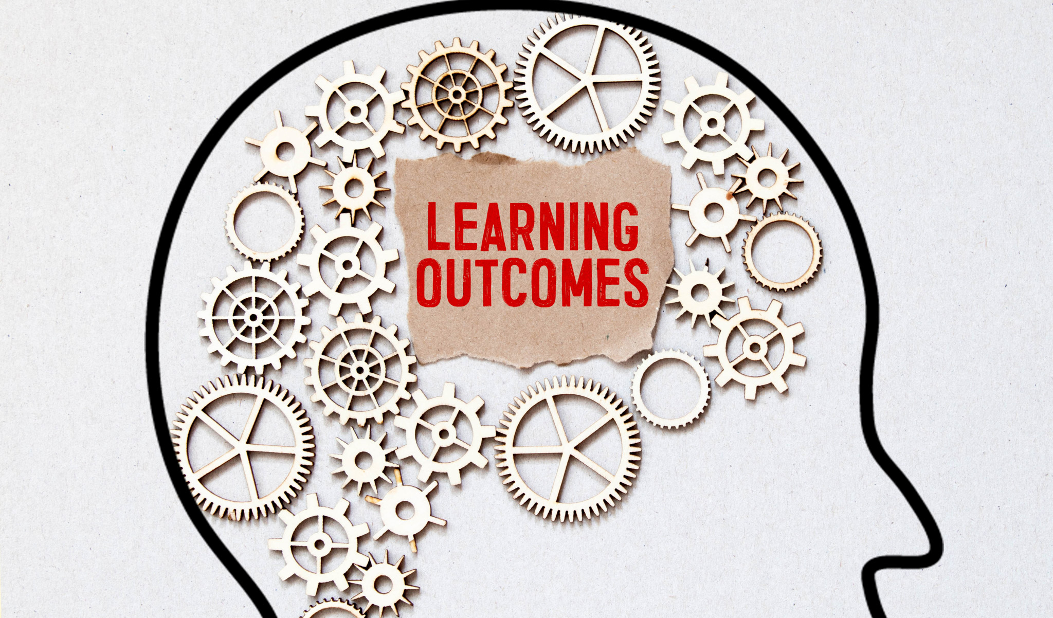 An outline of a head filled with gears and the words 'learning outcomes' inside