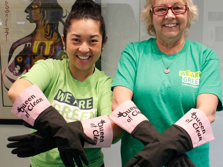 two volunteers showing off their rubber gloves that say "Queen of Clean" on them