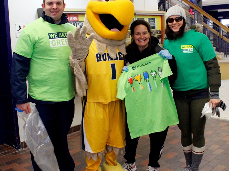three volunteers posing with the humber hawk mascot