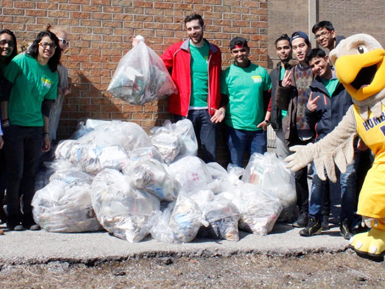 a group of volunteers posing with a pile of full garbage bags 