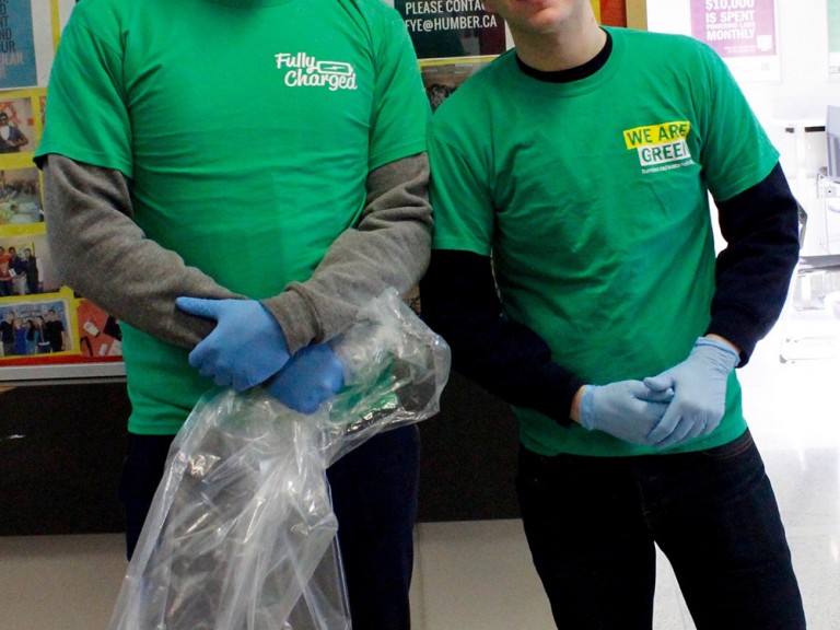 two volunteers posing holding plastic garbage bags 