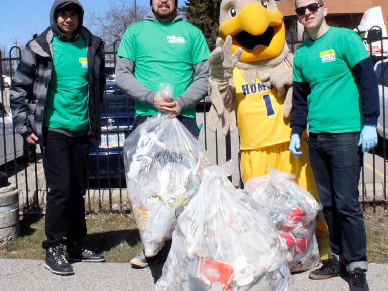 humber hawk mascot posing with three volunteers and three full trash bags