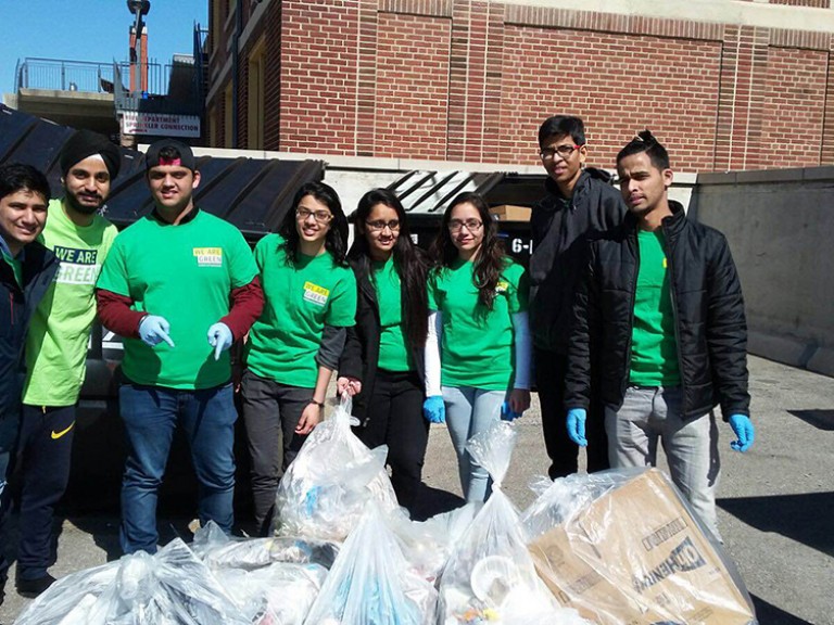 a group of volunteers by the dumpsters with their full trash bags