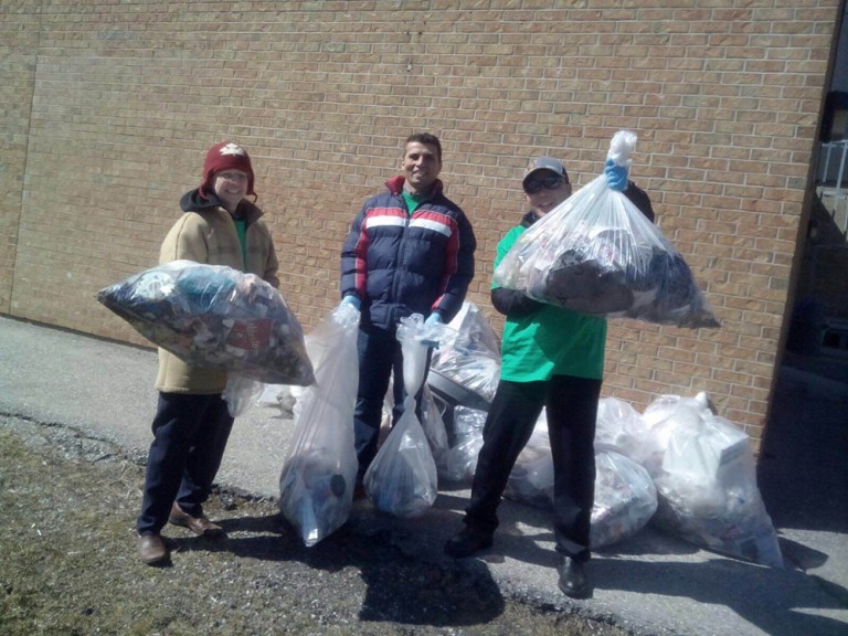 three volunteers showing all the trash they collected