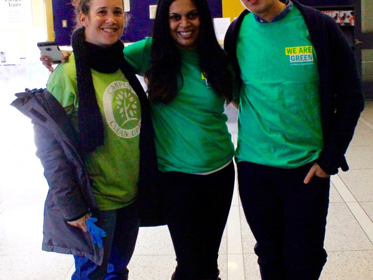 three volunteers posing in green shirts