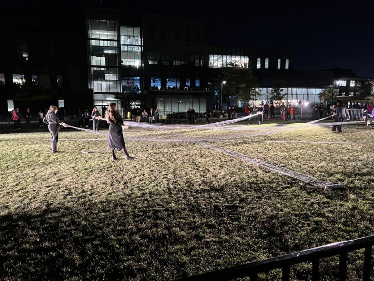 People holding string over the grass at night
