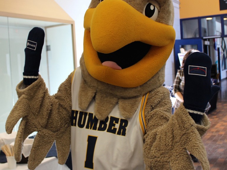 humber hawk mascot wearing mittens and posing for photo