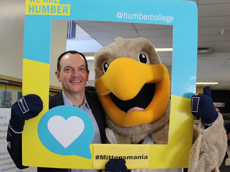 Chris Whitaker and humber hawk mascot holding up a photo frame