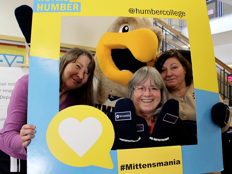 three women posing with the humber hawk mascot