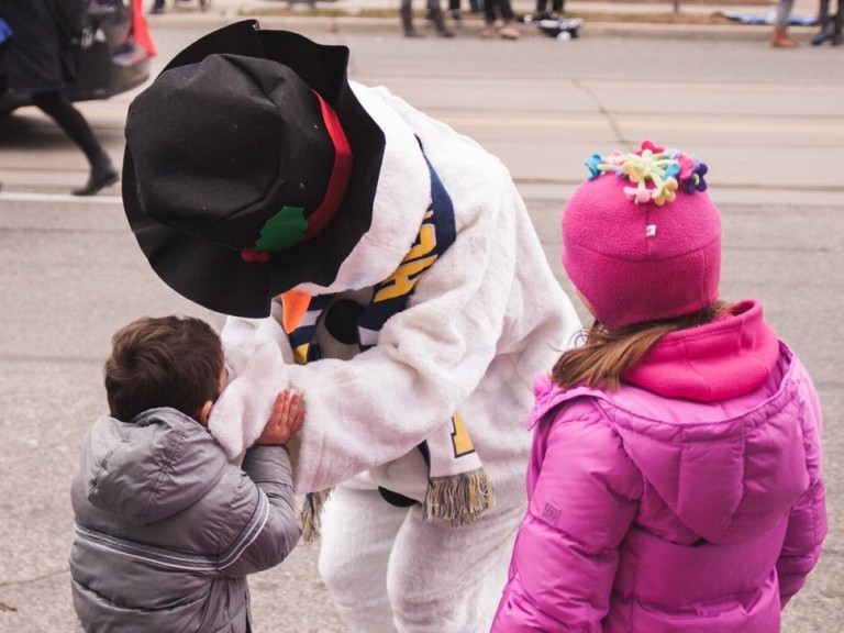 person dressed as a snowman interacting with two kids in the crowd