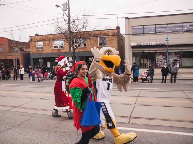 humber hawk mascot and person in elf costume waving to the crowd