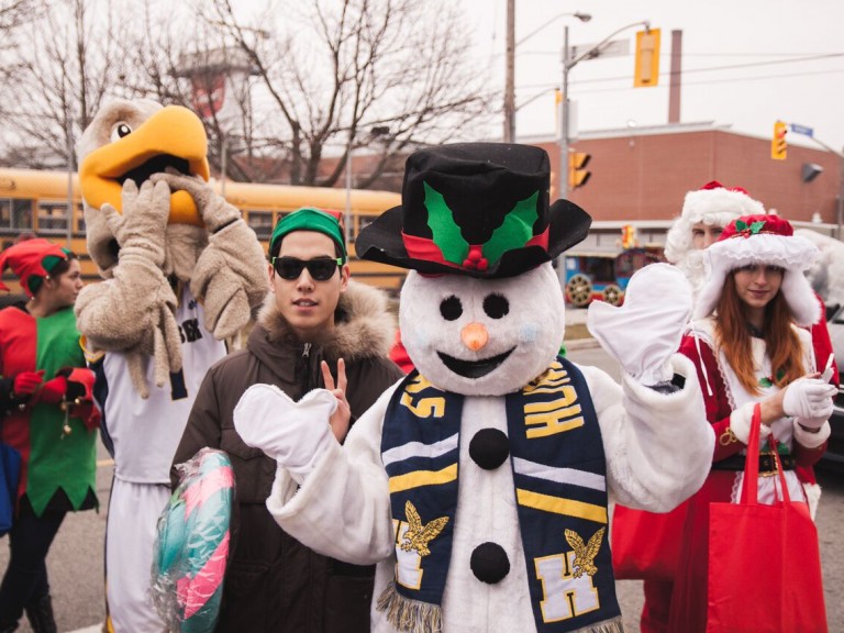 humber hawk mascot posing with the person in the snowman suit and a person holding a giant lolly pop