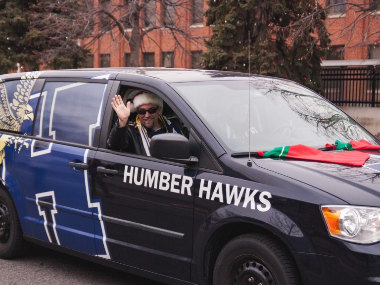 man wearing a santa hat sitting in the humber hawk car waving