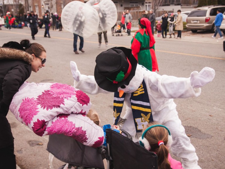 person in snowman costume interacting with kids in the crowd