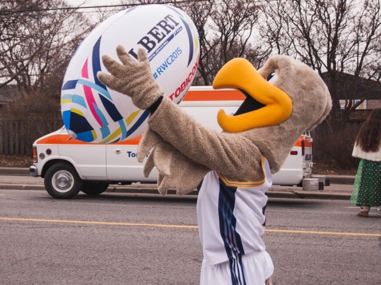 Humber hawk mascot holding a large blow-up rugby ball