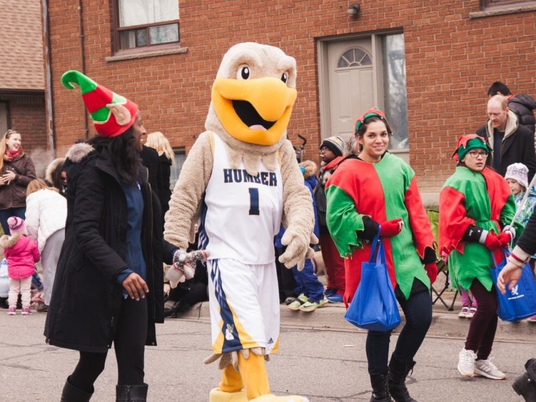 humber hawk mascot walking with three people dressed as elves