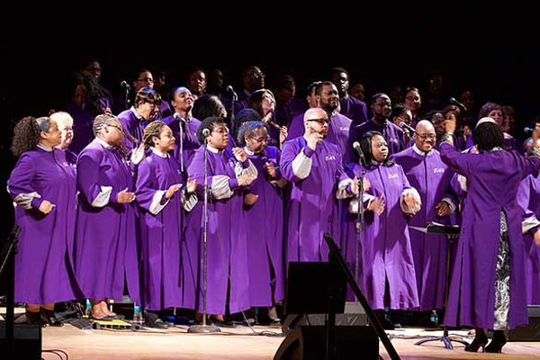 choir dressed in purple gowns singing on stage