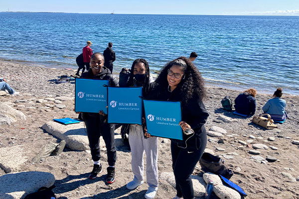 Students at the beach holding Humber Signs
