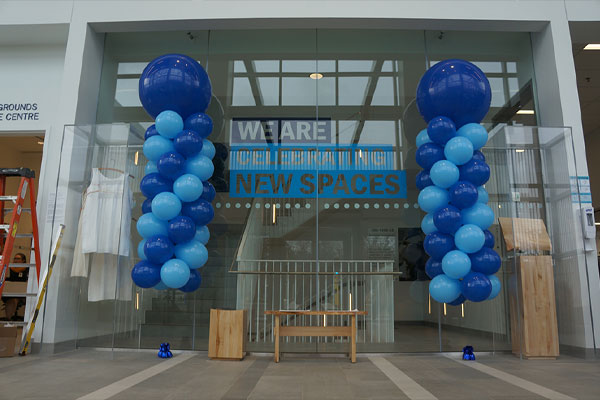 balloons outside of glass door that says we are celebrating new spaces